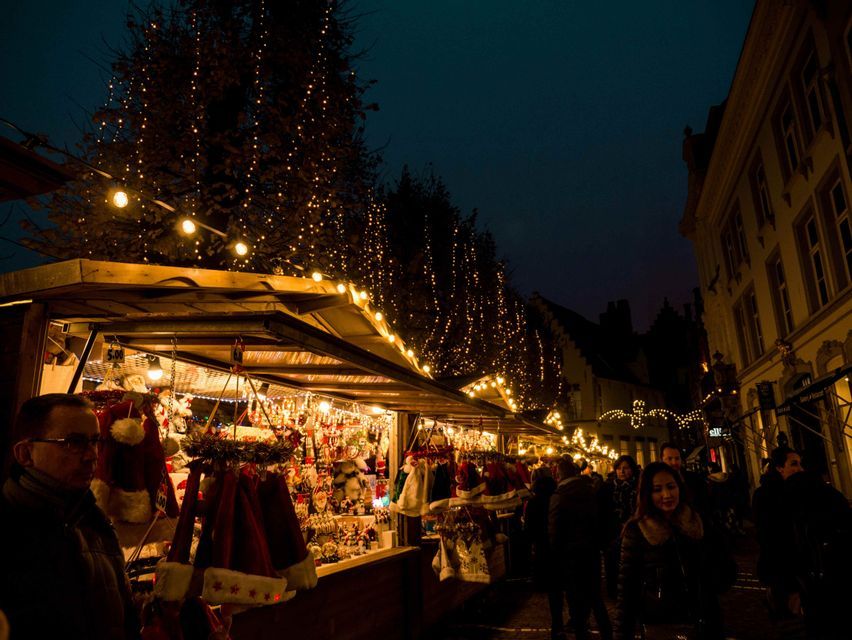 Un vivace mercatino di Natale di notte, con bancarelle illuminate da lucine che vendono decorazioni festive ai clienti.