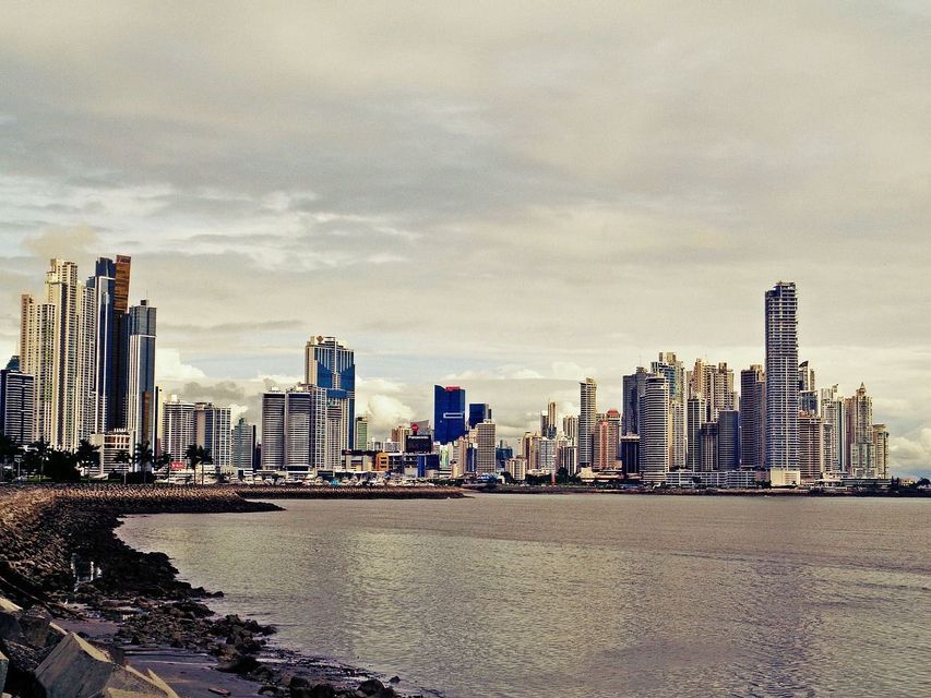 Lo skyline di una moderna città costiera con numerosi grattacieli, visto da una costa rocciosa attraverso l'acqua.