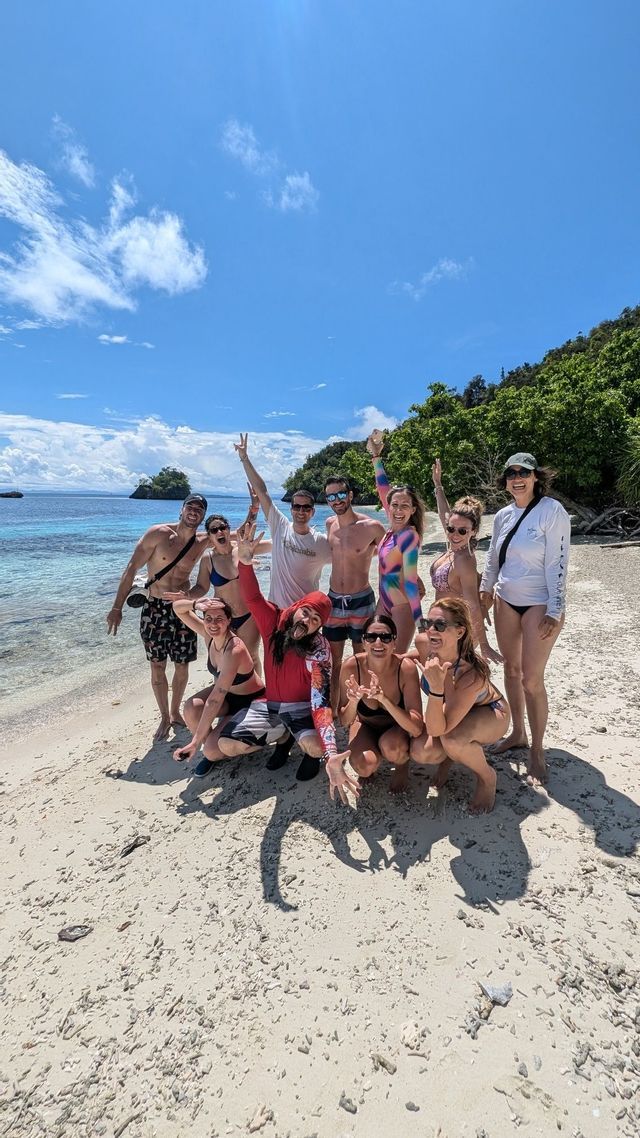 Un grupo de WeRoad en bañador posando en una playa de arena blanca y aguas turquesas.