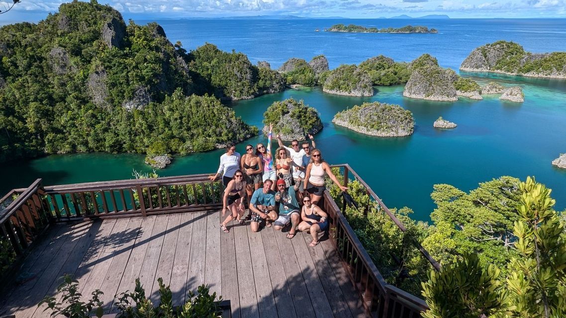 Un grupo de WeRoad posa para una foto en un mirador de madera, con vistas a una bahía tropical repleta de numerosas islas verdes y rocosas.