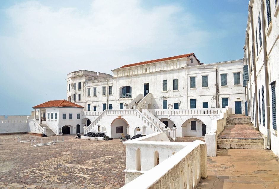 Der Kopfsteinpflasterhof einer großen, weißen historischen Festung mit Außentreppen, dunklen Fensterläden und Terrakottadächern.
