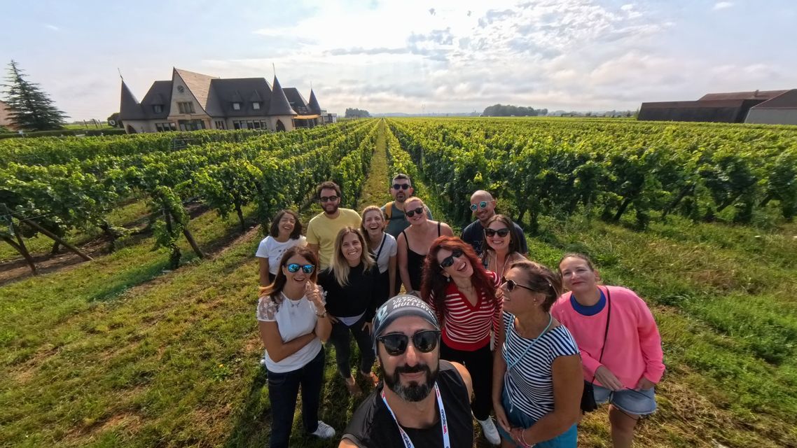 Eine WeRoad-Gruppe macht ein Selfie in einem großen Weinberg mit einem Schloss im Hintergrund.