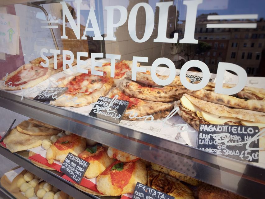 Una vetrina di vari cibi di strada italiani, come pizza e calzoni, con 'Napoli Street Food' scritto sul vetro