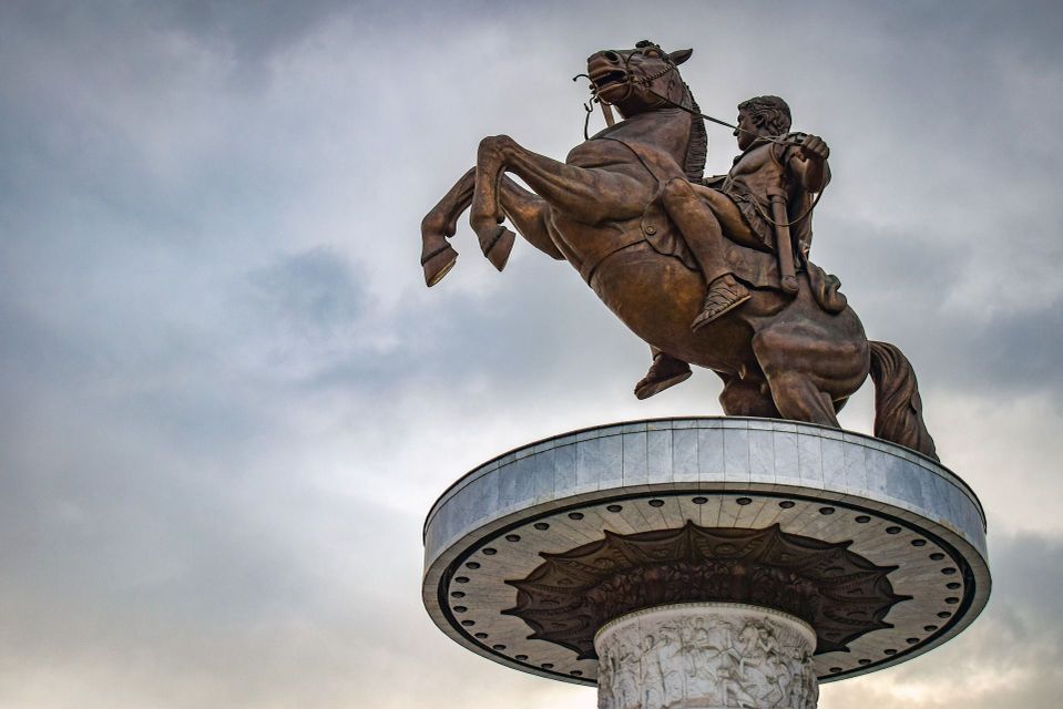 Una ripresa dal basso di una grande statua equestre in bronzo su un piedistallo circolare, con il cavallo che si impenna contro un cielo nuvoloso.