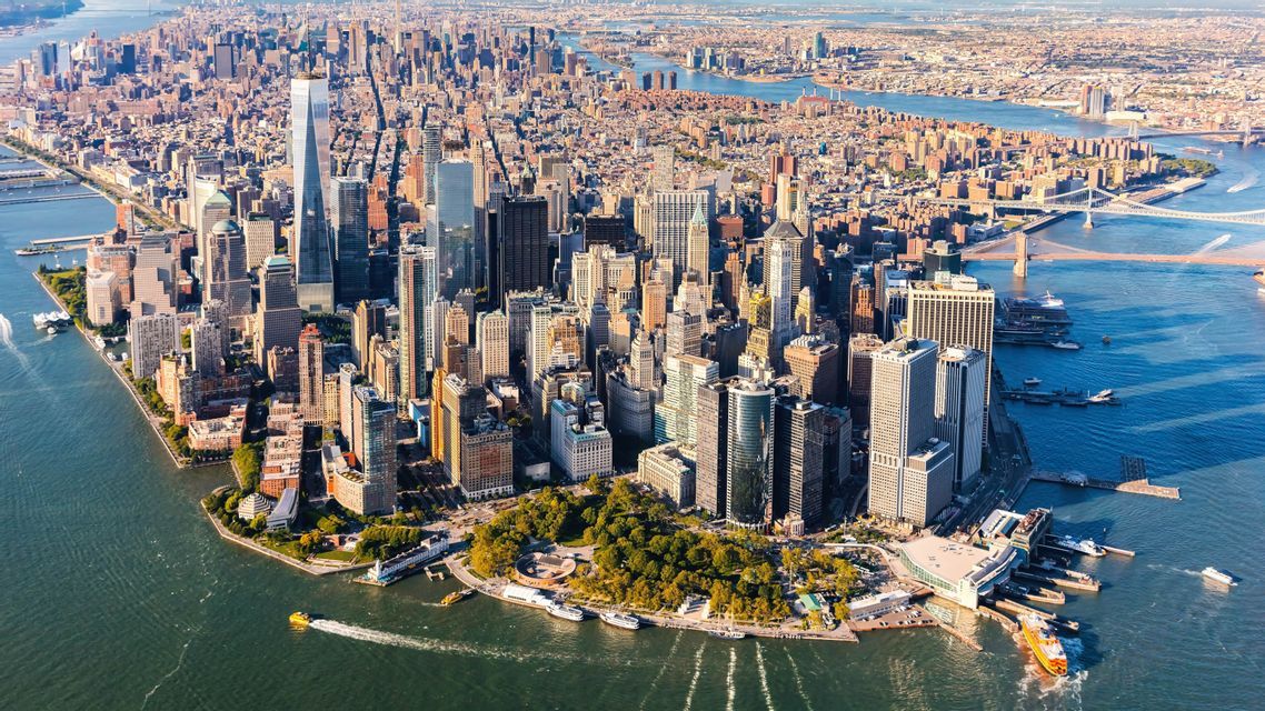 Vista aerea dello skyline di Lower Manhattan, con densi grattacieli circondati dai fiumi in una giornata di sole.