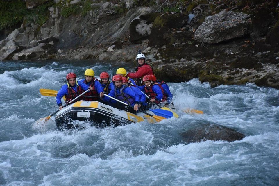Un groupe WeRoad en casques et gilets de sauvetage navigue un radeau gonflable dans des rapides tumultueux.