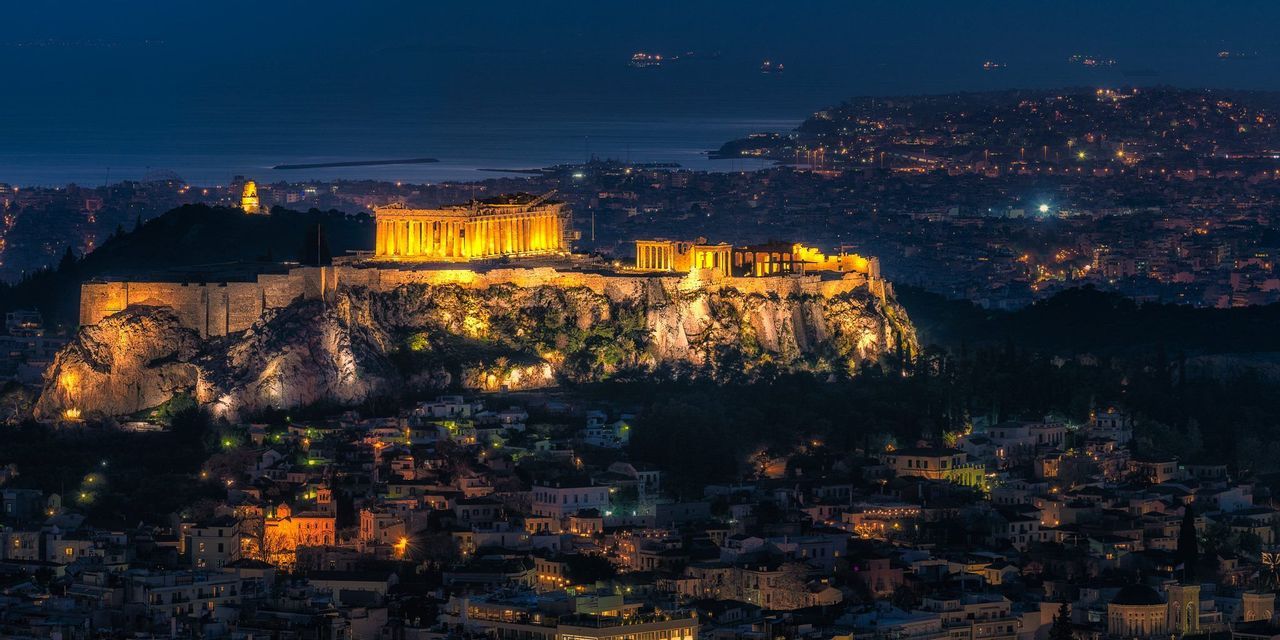 L'antica Acropoli è splendidamente illuminata di notte, dominando le luci della vasta città e il mare in lontananza.