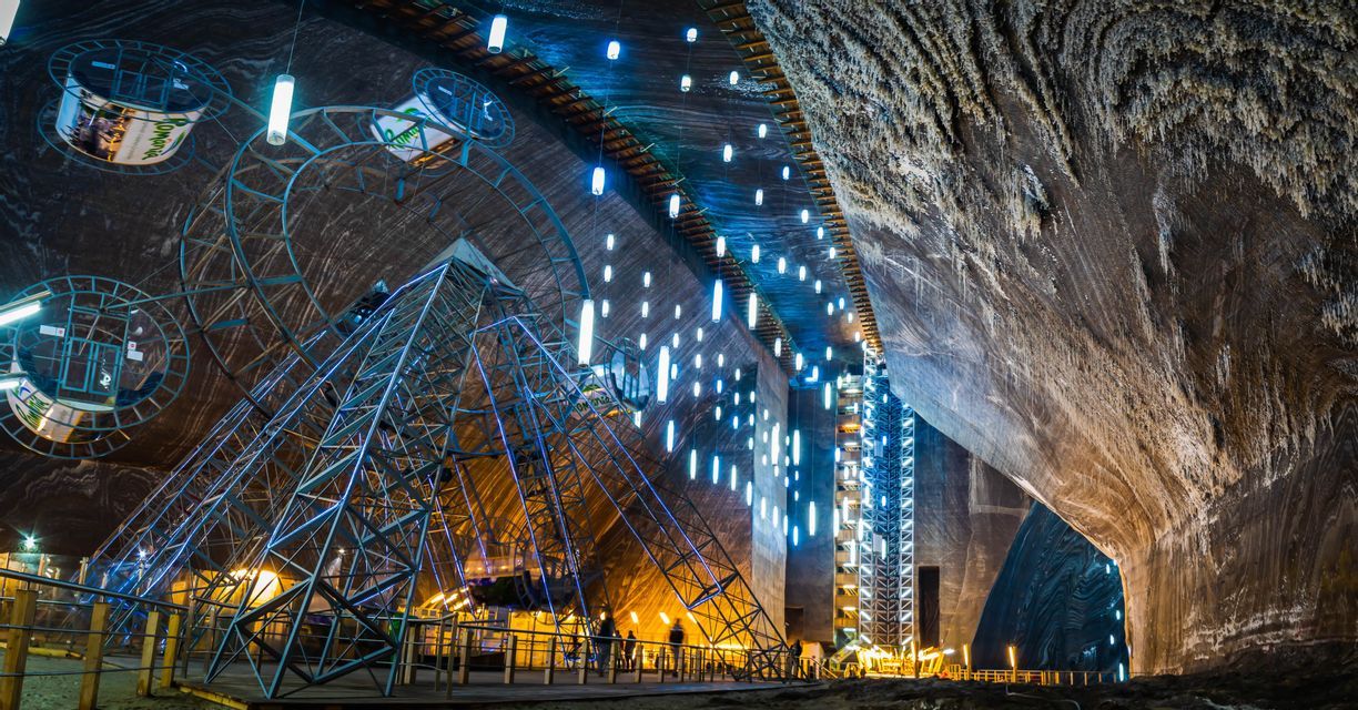 Una grande ruota panoramica con luci blu si erge all'interno di una vasta caverna rocciosa illuminata da decine di luci sospese.
