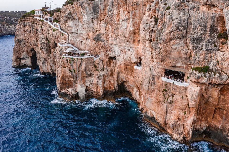 Restaurants and viewing platforms built into the side of a large cliff face overlooking the ocean.