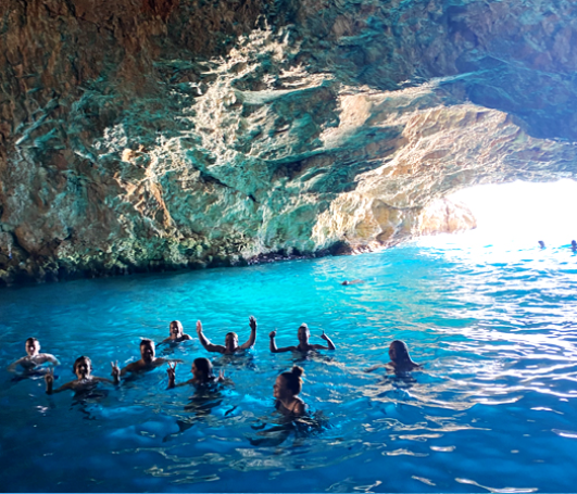 Un viaggio di gruppo WeRoad nuota e si diverte nelle acque azzurre e limpide all'interno di una grande grotta marina.
