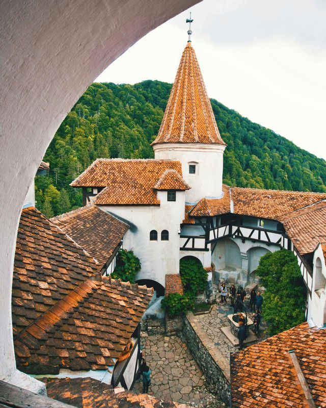 Un viaje en grupo de WeRoad se encuentra en el patio empedrado de un castillo histórico con paredes blancas y tejados de tejas naranjas