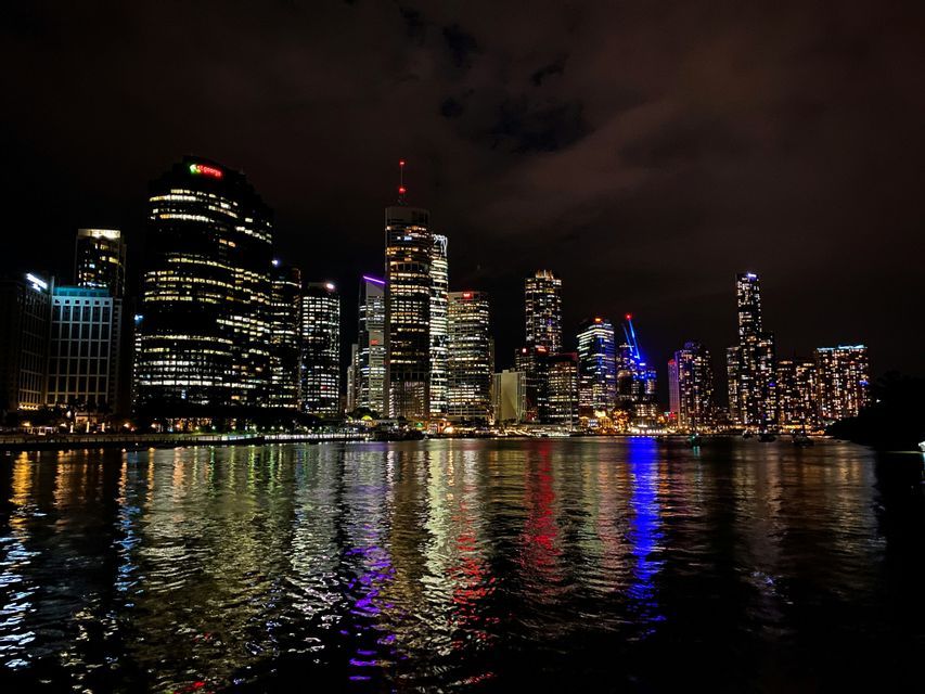 Un horizon urbain moderne illuminé la nuit, avec les lumières des bâtiments se reflétant sur la surface de l'eau.