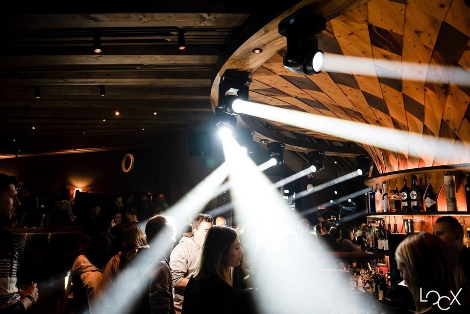 Viaggio di gruppo WeRoad che socializza in una discoteca buia, illuminata da potenti faretti provenienti da un soffitto in legno.
