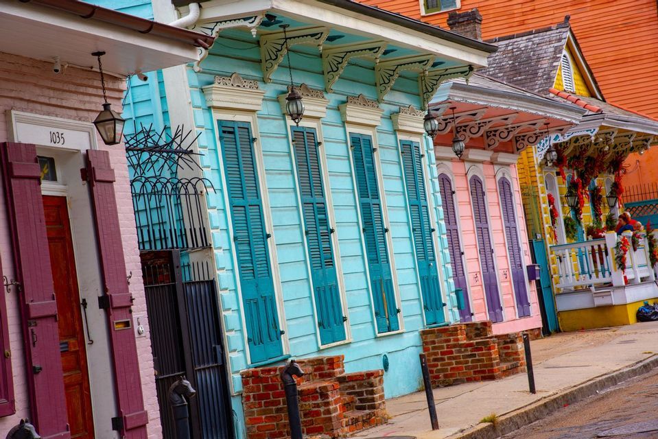 Vue en angle plongeant de maisons colorées aux volets contrastants et détails ornementés le long d'une rue citadine.