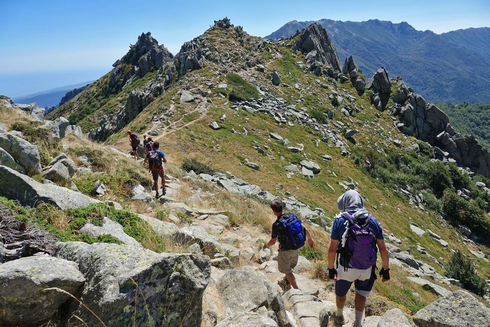 Un voyage de groupe WeRoad en randonnée le long d'une crête rocheuse sous un ciel dégagé.