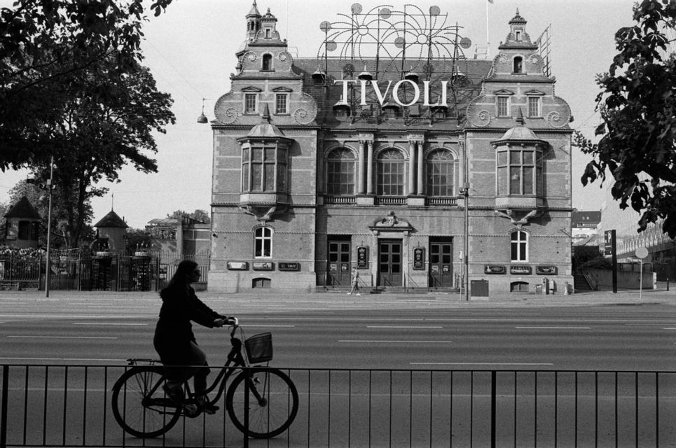 Una persona in bicicletta passa davanti all'ornato edificio di Tivoli in questa fotografia in bianco e nero.