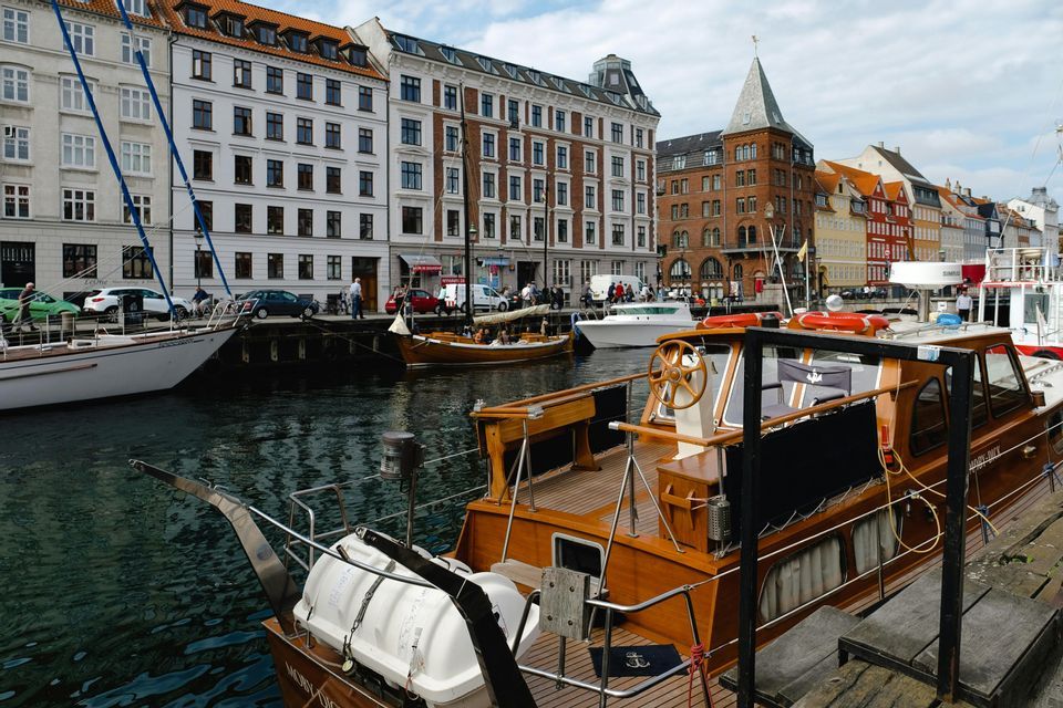 Un motoscafo in legno è ormeggiato in un canale cittadino, con altre imbarcazioni ed edifici storici che costeggiano il lungomare.
