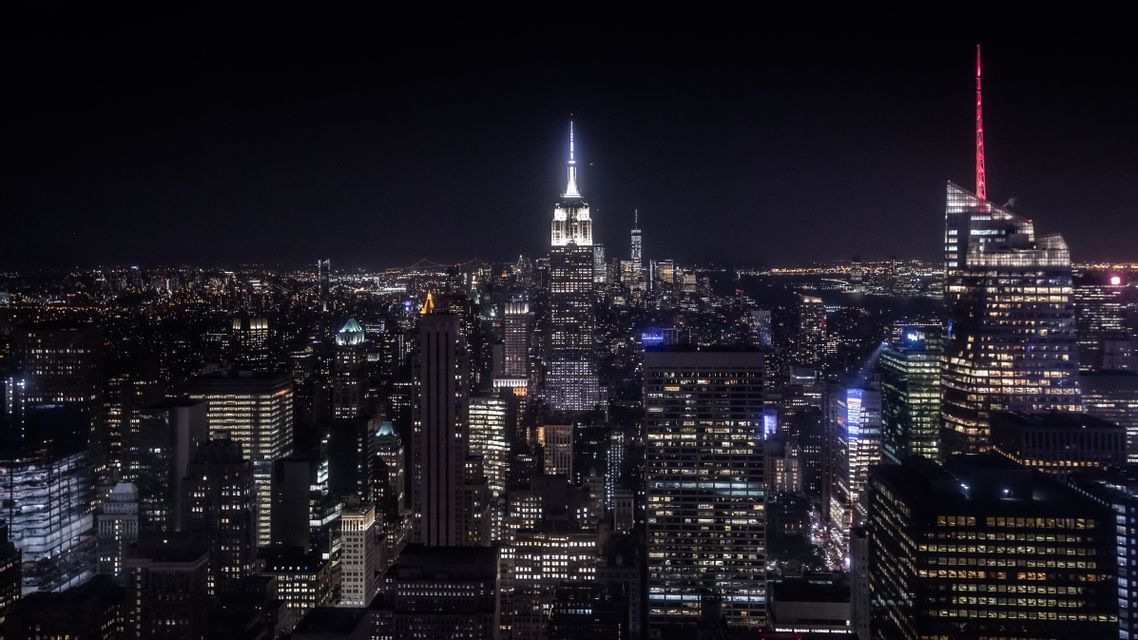 Vue aérienne d'une vaste ligne d'horizon urbaine la nuit, avec d'innombrables gratte-ciel illuminés sur le ciel sombre.