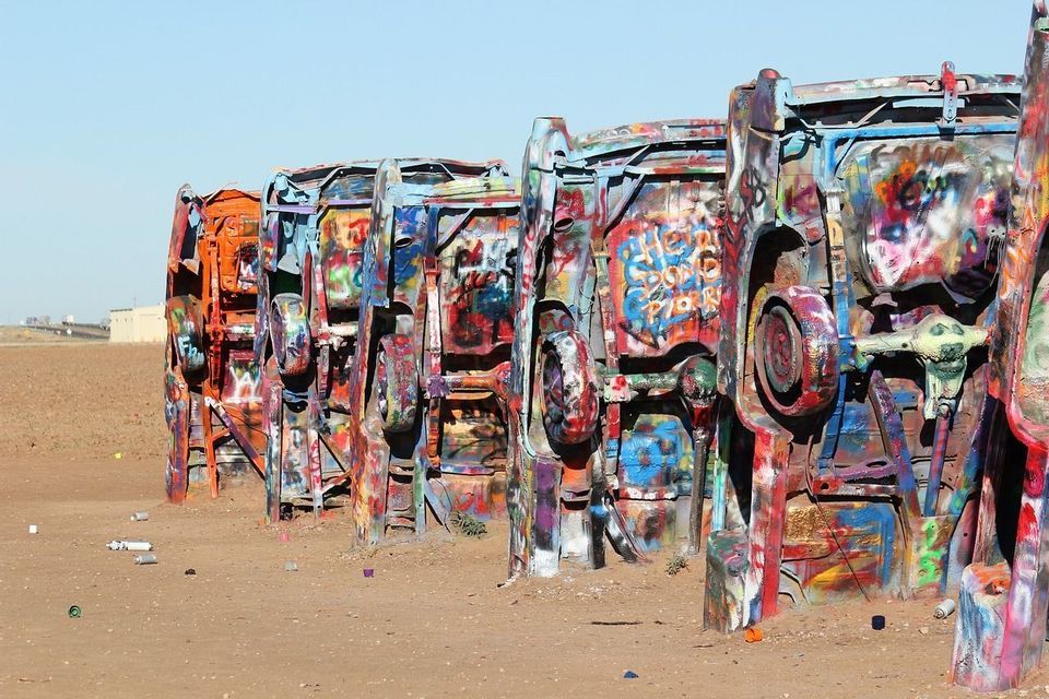 Una hilera de coches están enterrados de morro en la tierra, con sus bajos cubiertos de coloridas capas de grafitis.