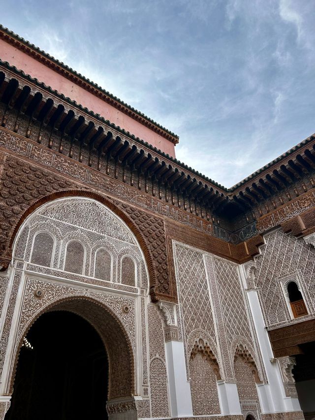 Una vista en ángulo bajo de la esquina ornamentada de un edificio con tallas detalladas en madera marrón, patrones de estuco blanco y un gran arco.