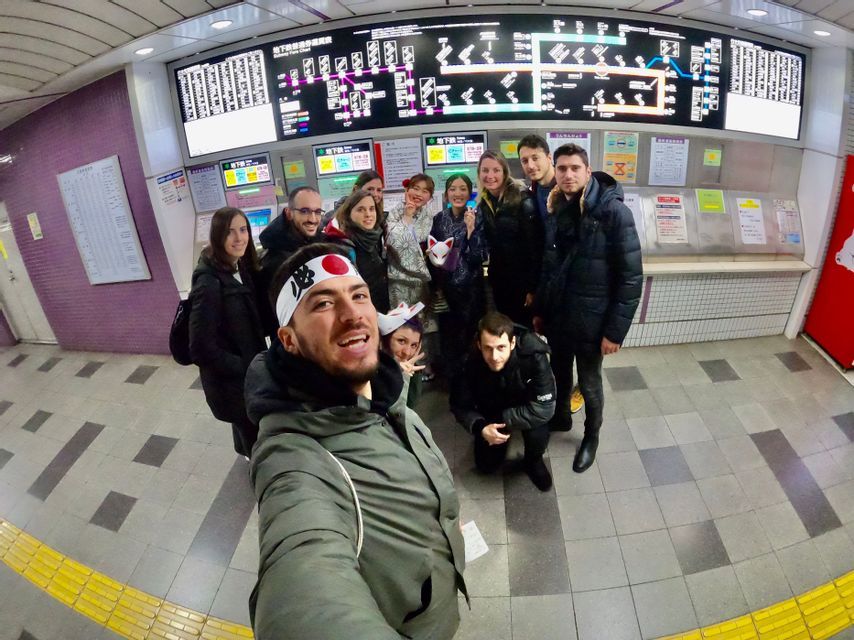 Un groupe WeRoad en voyage fait un selfie de groupe dans une station de métro, devant une grande carte électronique.