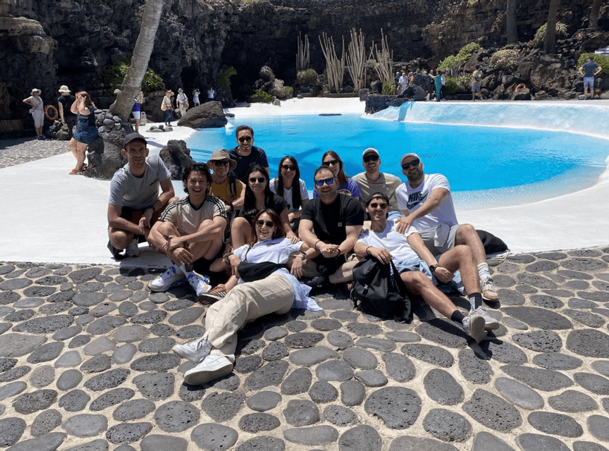 Un viaggio di gruppo WeRoad in posa per una foto su un patio in pietra accanto a una piscina azzurra brillante circondata da roccia vulcanica.