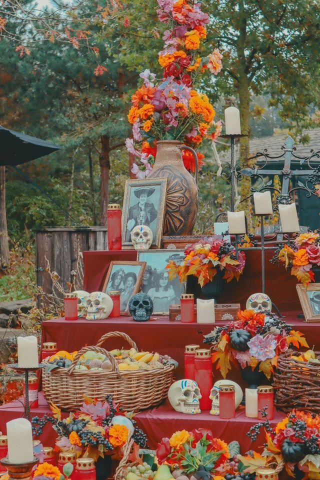 Un altare all'aperto decorato con foto incorniciate, teschi di zucchero, fiori, candele e frutta per una celebrazione del Giorno dei Morti.