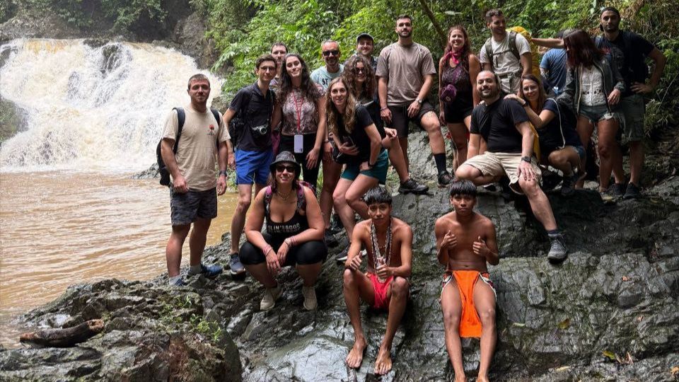 Un viaggio di gruppo WeRoad in posa per una foto su delle rocce accanto a una cascata in una giungla lussureggiante.
