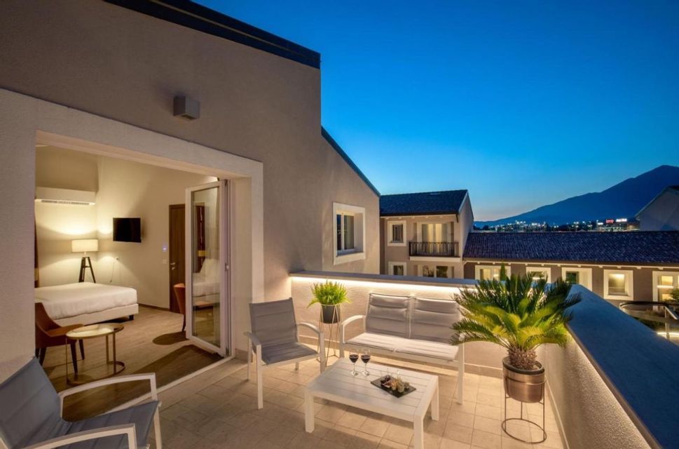 Un balcone arredato dell'hotel al tramonto, con vino e stuzzichini su un tavolo e una vista sulle montagne in lontananza.