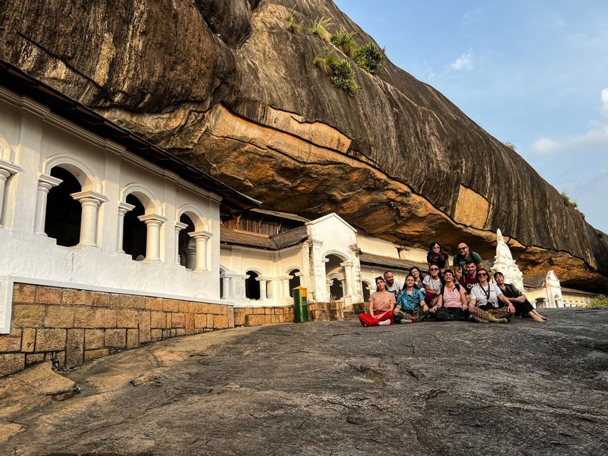 Un gruppo WeRoad siede su una grande roccia di fronte a un tempio bianco costruito nella scogliera.