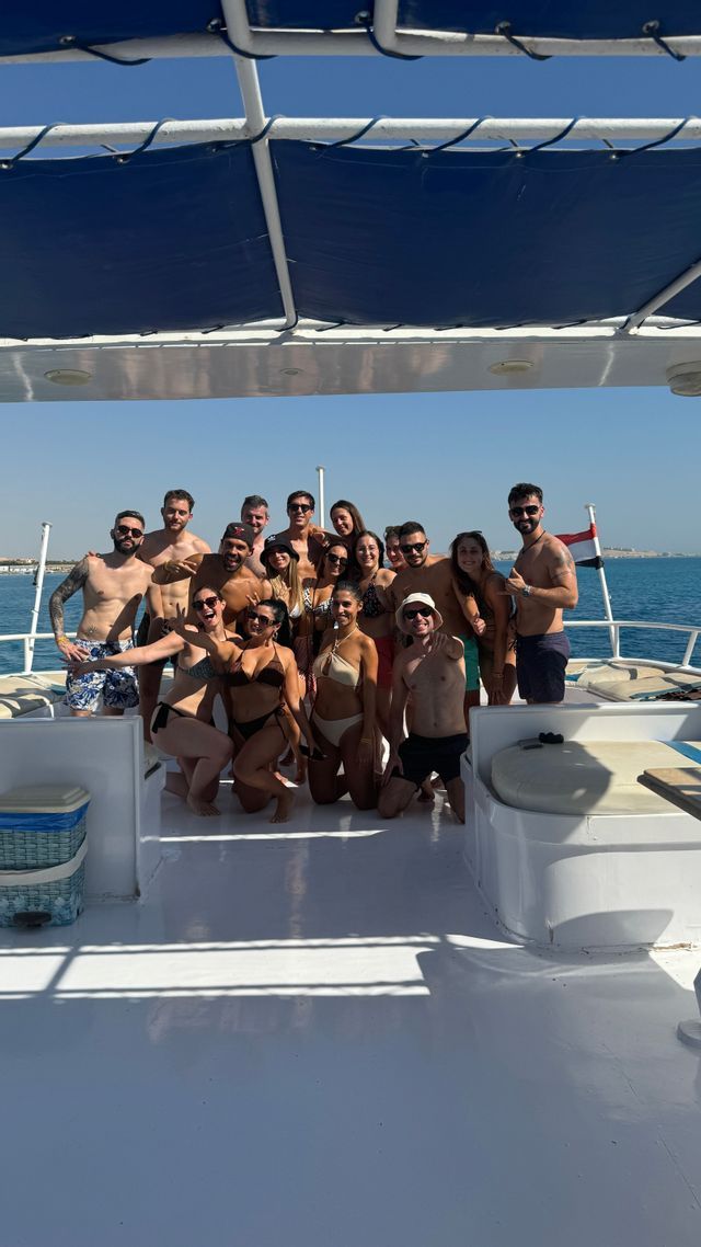 Un viaggio di gruppo WeRoad in posa per una foto sul ponte soleggiato di una barca con il mare sullo sfondo.