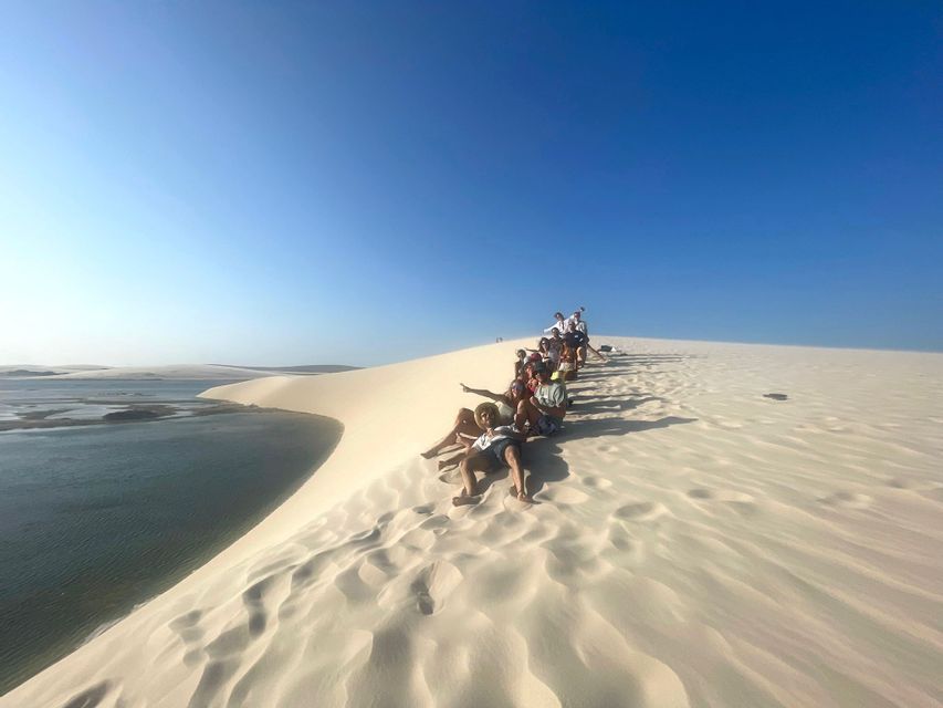 Un gruppo WeRoad in fila su una duna di sabbia bianca che si affaccia su una laguna sotto un cielo azzurro.