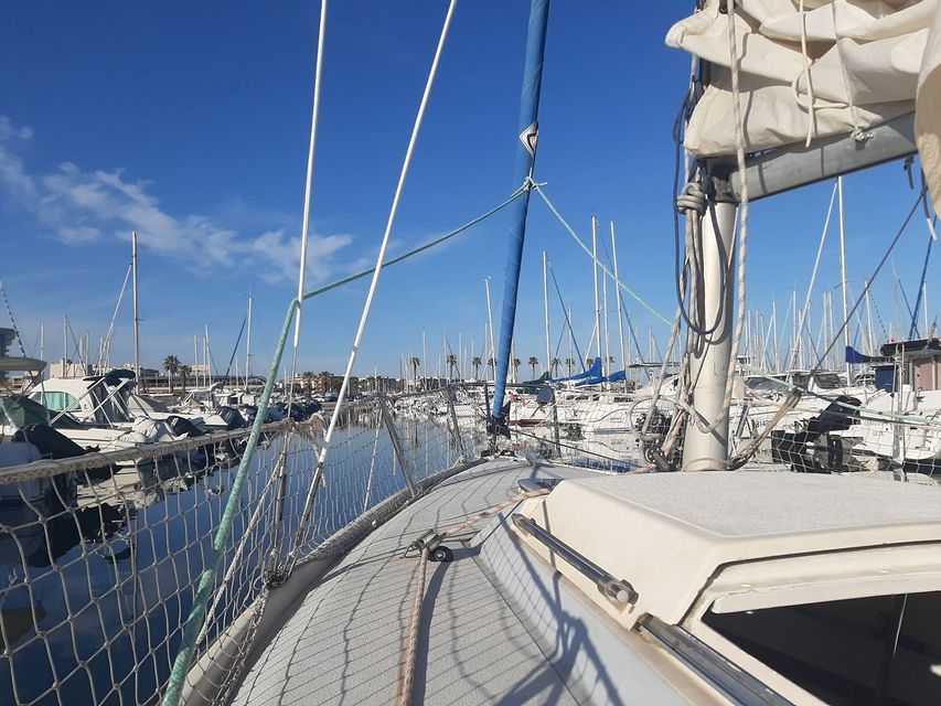 Vue depuis le pont d'un voilier amarré dans une marina remplie d'autres navires par une journée ensoleillée.