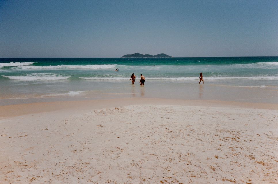 Un grupo de WeRoad de pie en las aguas poco profundas del mar, en una playa de arena con una isla distante en el horizonte.