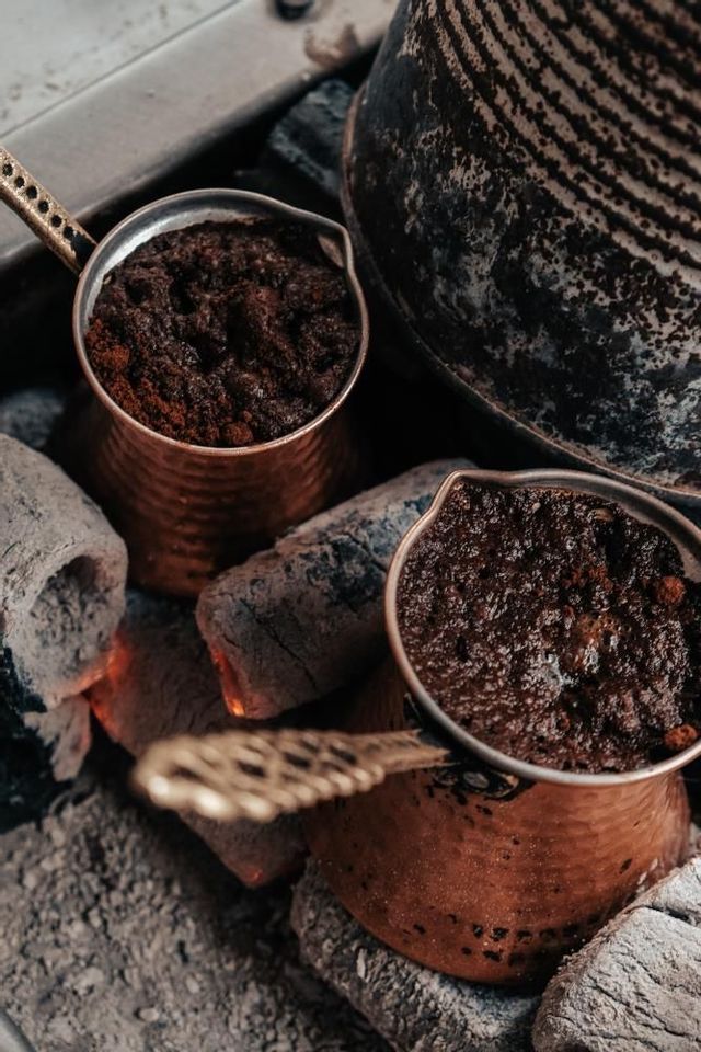 Due tradizionali bricchi di rame con caffè in lenta infusione su braci ardenti.