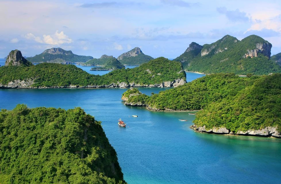 Una vista aerea di un arcipelago con isole verdi e lussureggianti, acqua blu calma e diverse piccole barche che navigano.