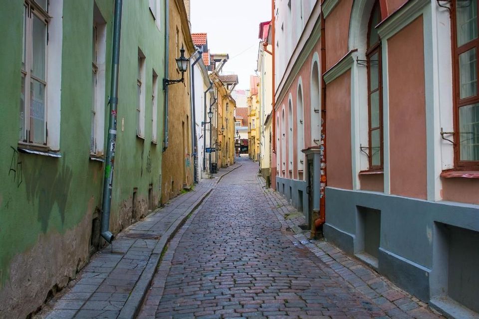 Eine schmale Kopfsteinpflastergasse schlängelt sich zwischen farbenfrohen, historischen Gebäuden in einer europäischen Gasse.