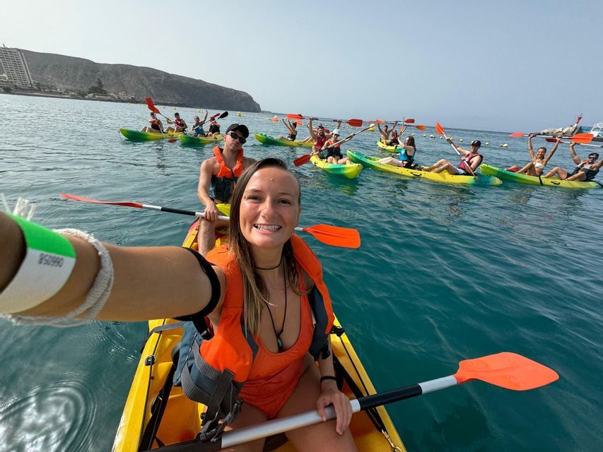 Eine Frau macht während einer WeRoad-Gruppentour auf See ein Selfie von ihrem Kajak aus, im Hintergrund sind andere Kajakfahrer zu sehen.
