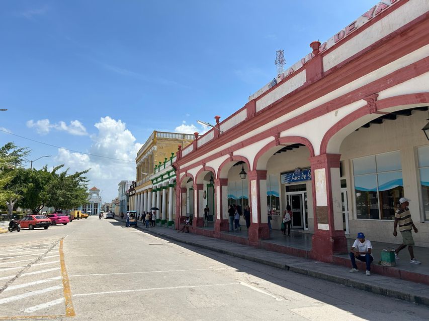 Una vista de la calle de edificios coloniales coloridos con largos soportales cubiertos bajo un cielo azul brillante.