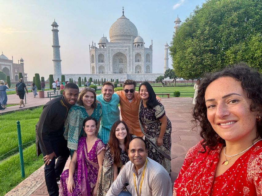 Un groupe WeRoad en tenue traditionnelle colorée pose pour un selfie devant un mausolée en marbre blanc.