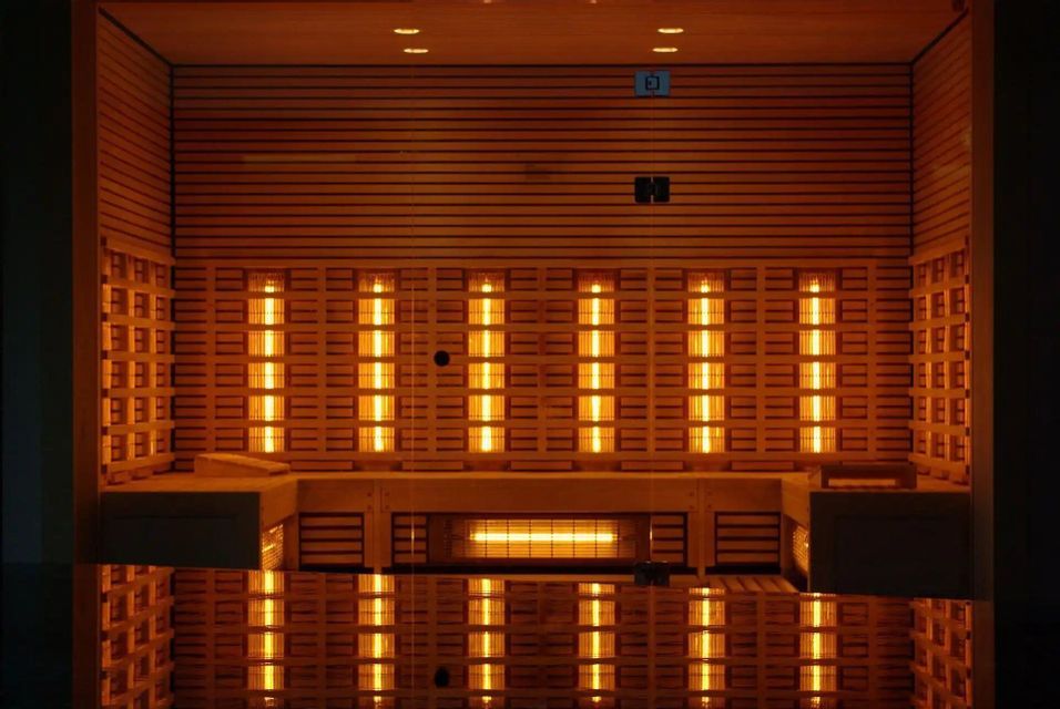 El interior de una sauna de infrarrojos de madera vacía con paneles calefactores naranjas brillantes en las paredes.