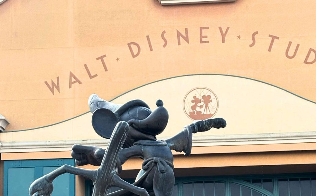Eine Bronzestatue von Micky Maus als Zauberlehrling vor dem Gebäude der Walt Disney Studios.