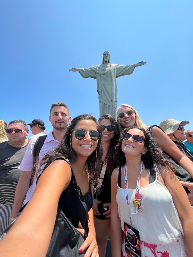 Eine WeRoad-Gruppenreise macht an einem sonnigen Tag ein lächelndes Selfie vor der Christus-Erlöser-Statue.
