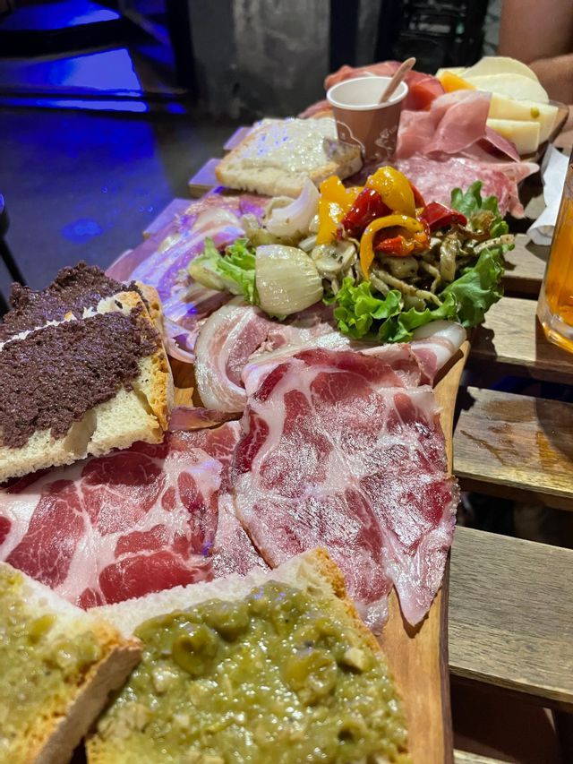 A close-up of a charcuterie board with cured meats, cheeses, various spreads on bread, and pickled vegetables.
