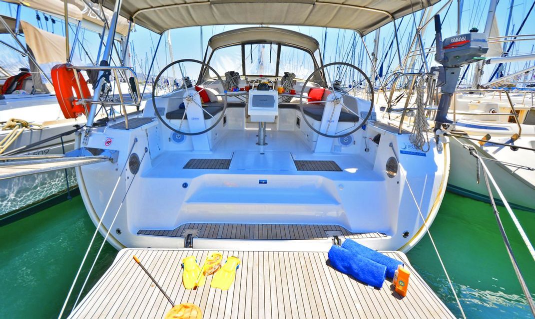 La poppa di una moderna barca a vela ormeggiata in un porto turistico, con due timoni nel pozzetto e attrezzatura per il nuoto sulla piattaforma da bagno.