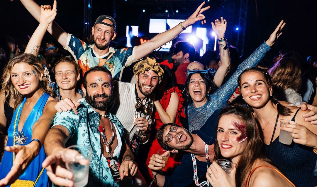 Un viaggio di gruppo WeRoad, con persone sorridenti e truccate per la festa, piene di glitter, a una festa notturna.