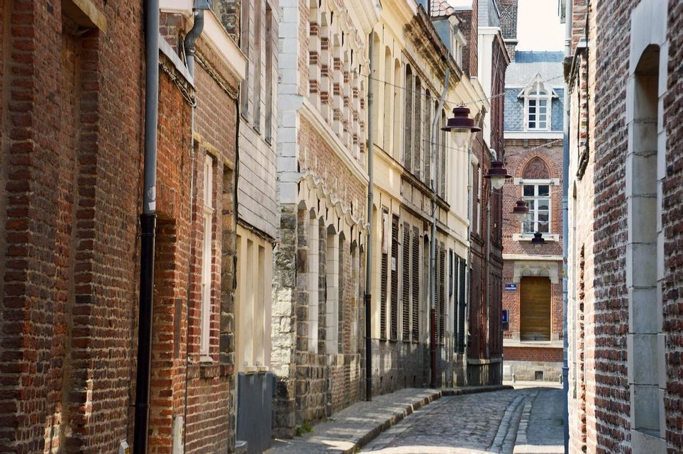 Une vue sur une étroite rue pavée vide bordée de bâtiments résidentiels en briques rouges.