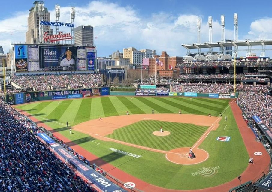 Un'ampia vista di una partita di baseball in uno stadio affollato con lo skyline della città visibile dietro il campo esterno.