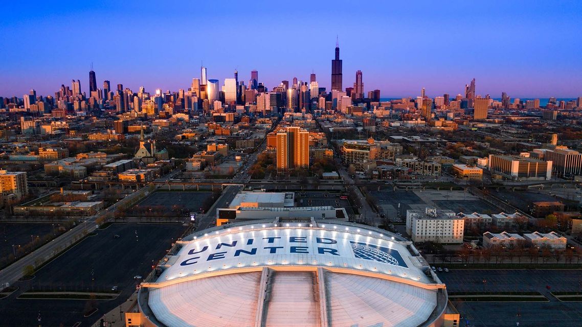 Una vista aerea del tetto a cupola dello United Center con lo skyline di Chicago visibile sullo sfondo contro un cielo crepuscolare.
