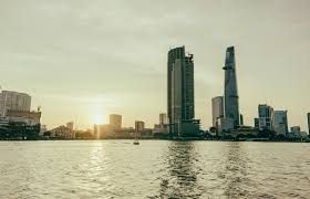 Lo skyline di una città con grattacieli moderni visto da oltre uno specchio d'acqua al tramonto.